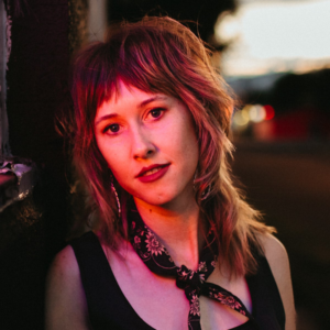 Patty McCrystal headshot - a white woman with a bandana tied around her neck and mid-length hair and bangs.